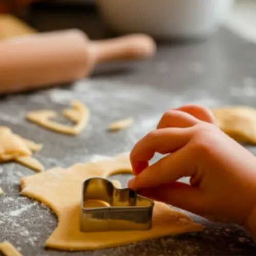 Cutting dough with a heart-shaped cookie cutter on a countertop.