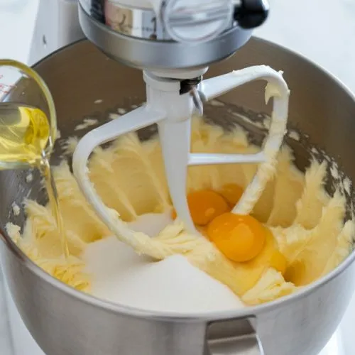 A stand mixer is mixing butter, sugar, eggs, and oil for a baking recipe.