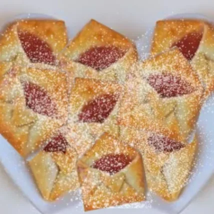 Jam-filled dough parcels shaped like envelopes, dusted with powdered sugar.