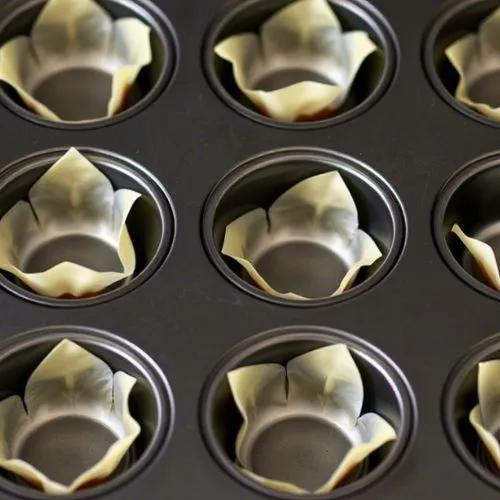 Muffin tin lined with Wonton wrappers for taco cupcake preparation.